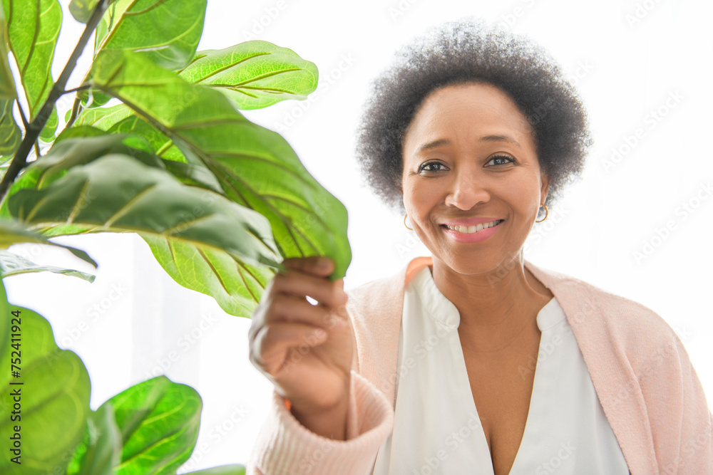 beautiful senior black American woman at home with plant beautiful senior black American woman at home with plant