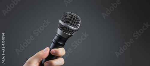 Journalist's hand holding microphone on grey background. photo