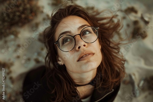 A woman with glasses is laying on the ground. She is looking up at something. The scene is peaceful and calm