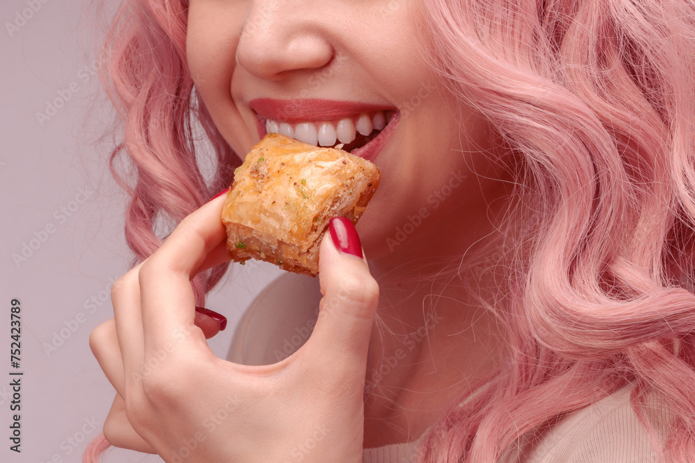 Woman with pink curly hair is eating baklava. Woman with pink curly hair is eating baklava.