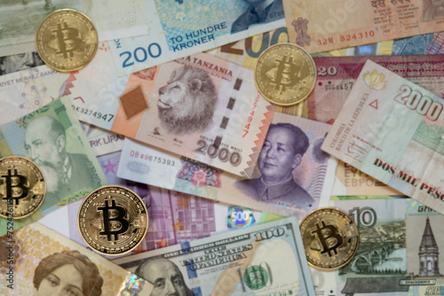 Gold Bitcoin coin on a defocused background of banknotes of different countries. Selective focus.
