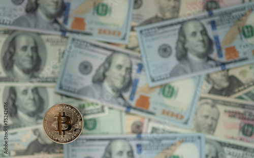 Bitcoin gold coin against the defocused background of dollar bills.