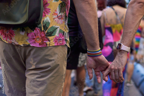 Gay couple holding hands while walking on a pride parade on the city downtown
