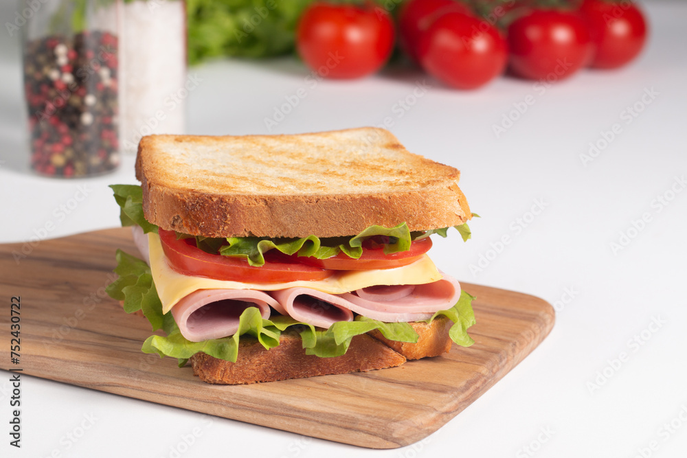 Close-up of two sandwiches with bacon, salami, prosciutto and fresh vegetables on rustic wooden cutting board. Club sandwich concept Close-up of two sandwiches with bacon, salami, prosciutto and fresh vegetables on rustic wooden cutting board. Club sandwich concept