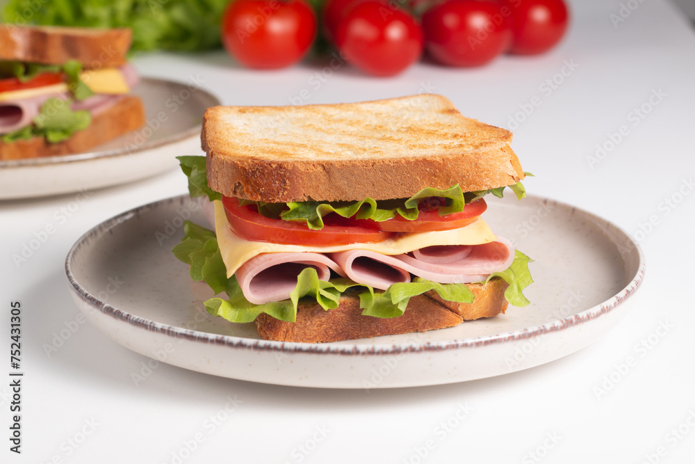 Close-up of two sandwiches with bacon, salami, prosciutto and fresh vegetables on rustic wooden cutting board. Club sandwich concept Close-up of two sandwiches with bacon, salami, prosciutto and fresh vegetables on rustic wooden cutting board. Club sandwich concept