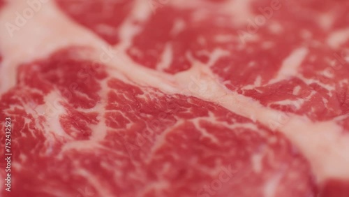 Fresh marbled beef with pepper, salt and rosemary close-up macro. Preparation to cook juicy steak on grill. Premium organic raw wagyu meat photo