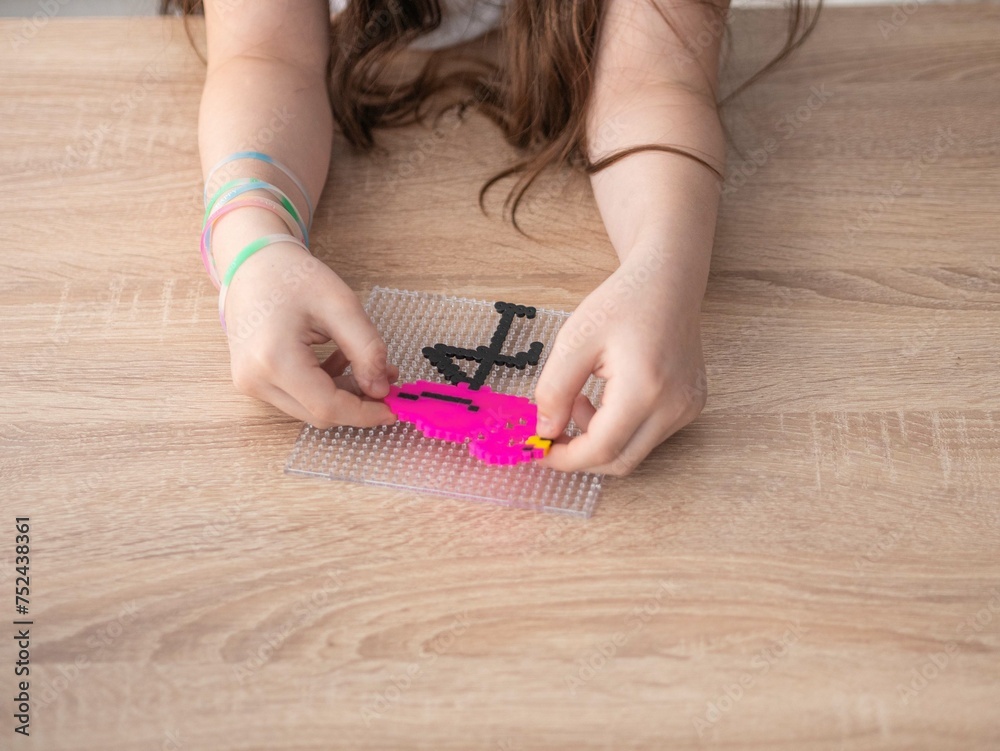Obraz premium A happy little girl looks at a pink flamingo toy made with her own hands from thermosetting material and smiles. The fourth stage. A finished craft made of plastic parts glued together by high tempera