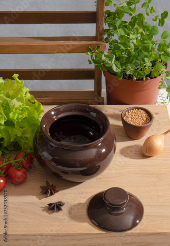 Baking dish on the kitchen table among vegetables and herbs