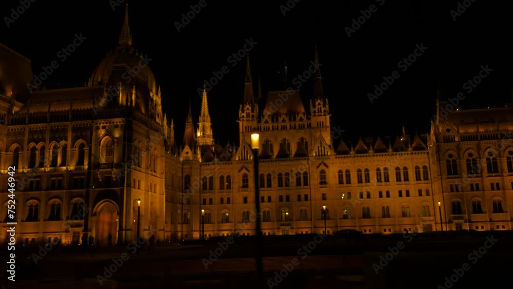 Driving car by illuminated budapest parliament. A view of public road against illuminated Budapest building during night time.