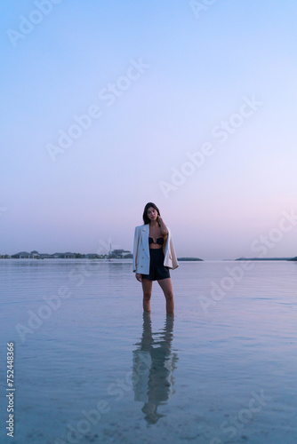 Portrait of a beautiful Middle eastern woman walking in the water wearing a jacket hugging herself 