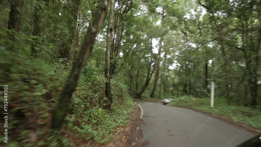 view of the country side road through the rain forest on the mountain in northern area of Thailand front camera view on the moving car through mountain road view of the country side road through the rain forest on the mountain in northern area of Thailand front camera view on the moving car through mountain road