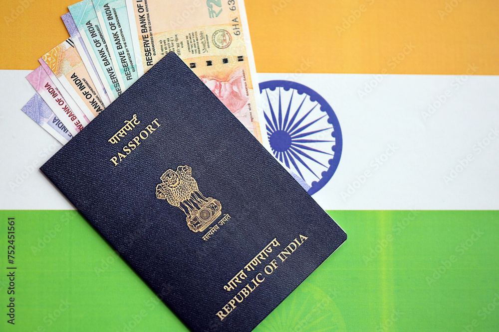 Blue Indian passport and Indian rupees money bills on flag background close up. Tourism and citizenship concept Blue Indian passport and Indian rupees money bills on flag background close up. Tourism and citizenship concept