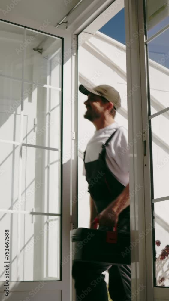 A man dressed in work attire, holding a toolbox, arrives at a woman's home to fix something. He appears ready and equipped to tackle the task at hand.Vertical A man dressed in work attire, holding a toolbox, arrives at a woman's home to fix something. He appears ready and equipped to tackle the task at hand.Vertical
