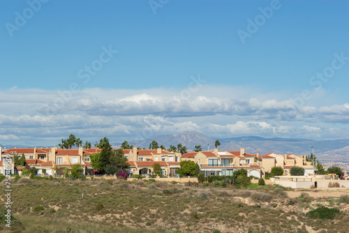Wallpaper Mural Residential buildings with mountain and sea views on a seashore. The coast on a sunny day. Townhouses against the blue sky and clouds. Alicante region in Spain Torontodigital.ca