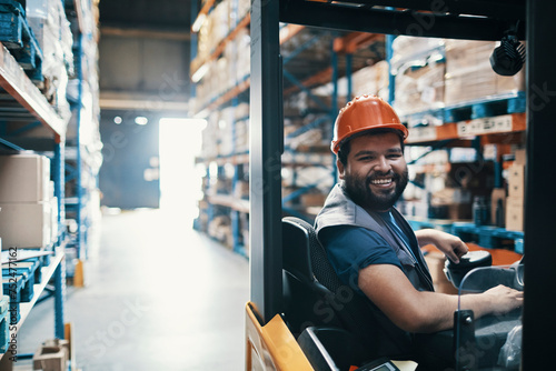 Smiling male forklift operator working in warehouse photo