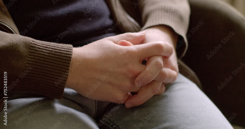 Close-up male hands. Close-up of interlocking fingers during person feeling insecure, anxious, or defensive. This gesture suggests that the individual is seeking comfort or reassurance. Close-up male hands. Close-up of interlocking fingers during person feeling insecure, anxious, or defensive. This gesture suggests that the individual is seeking comfort or reassurance.