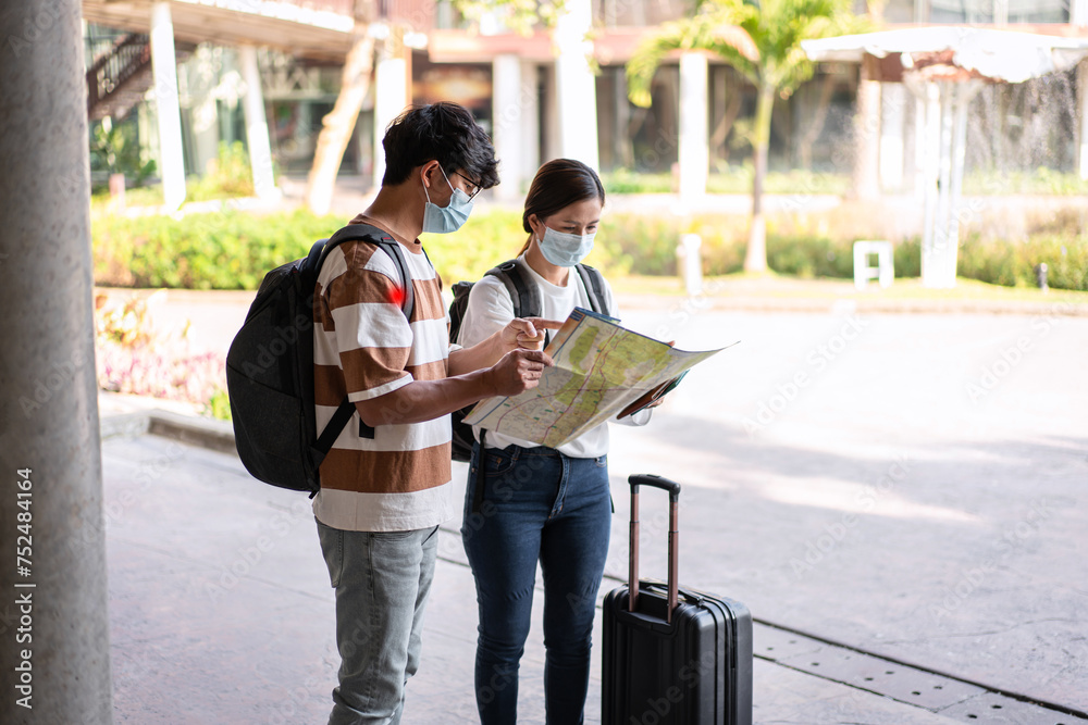 Tourist couple with luggage looking on the map to searching direction destination for honeymoon trip