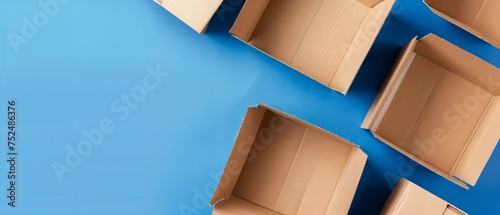 Open cardboard packaging boxes arranged on a vibrant blue background - overhead view of moving day concept