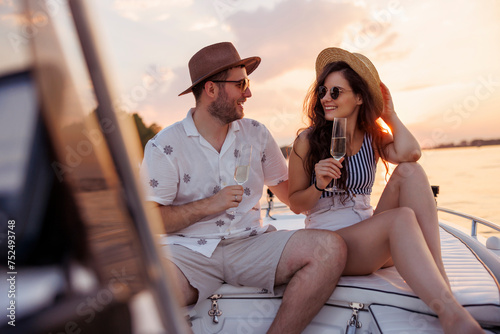 Couple drinking champagne while sailing to sunset on boat