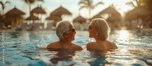 Middle aged joyful senior couple swimming pool luxury resort exotic vacation summer paradise 