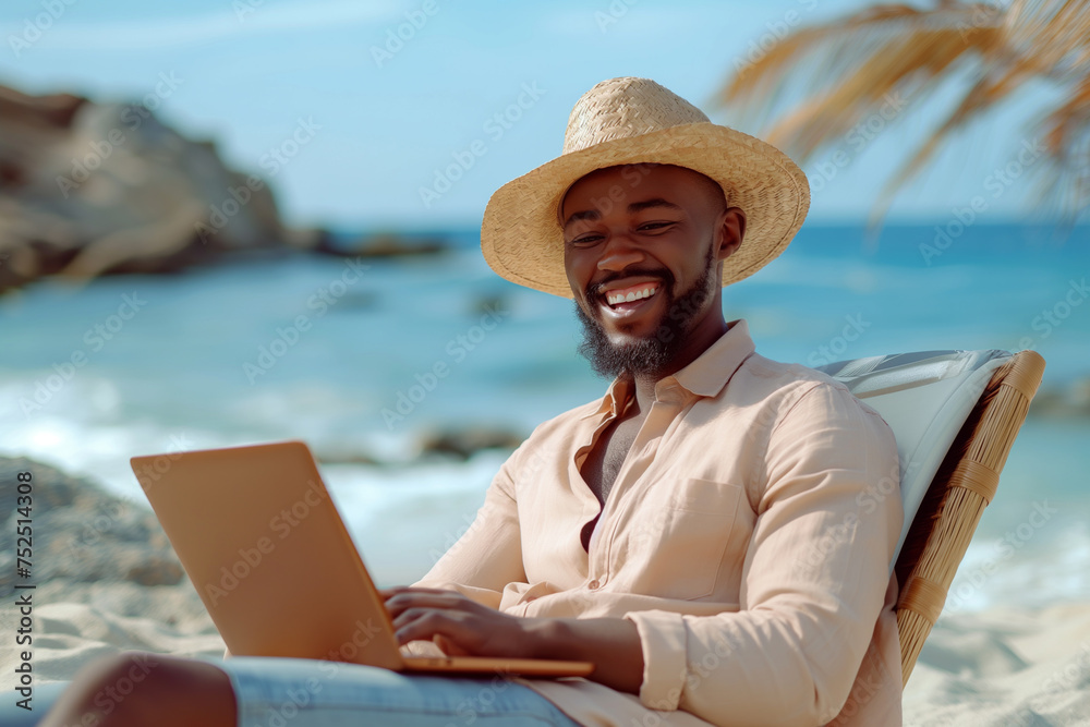 young man in a straw hat with a laptop relaxing on the beach, freelance concept
