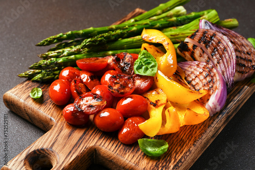 Grilled vegetables: asparagus,tomatos,onion on a wooden board on a black background photo