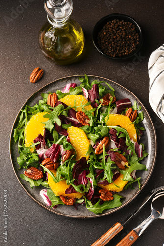 Arugula, orange and pecan salad. Radicchio salad on brown background