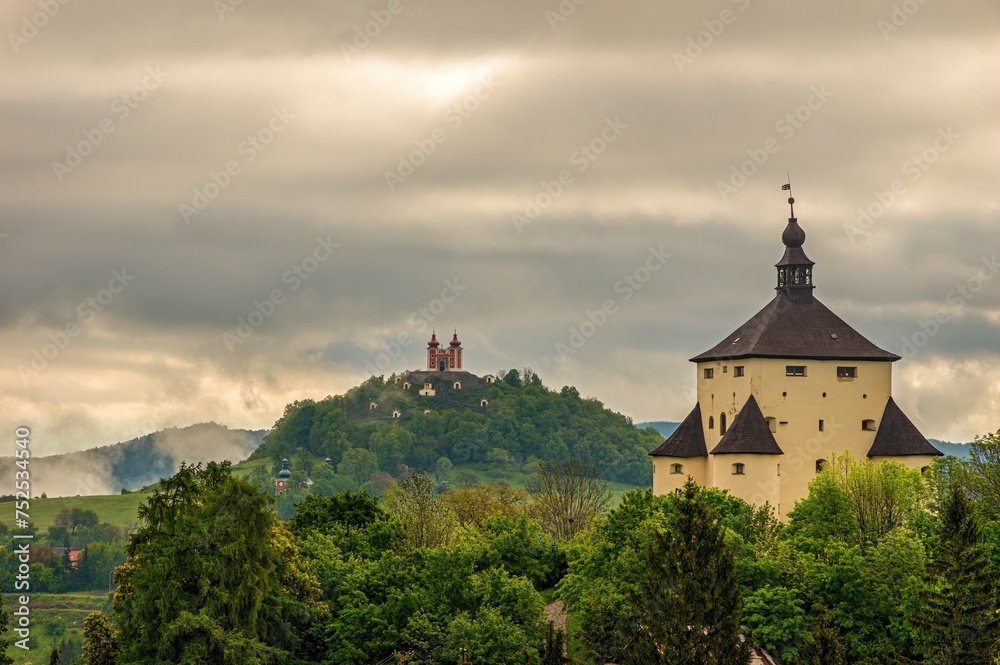 Fortified historical building in mountain landscape with hills after rain with fog. New Castle and Calvary in Banska Stiavnica, Slovakia