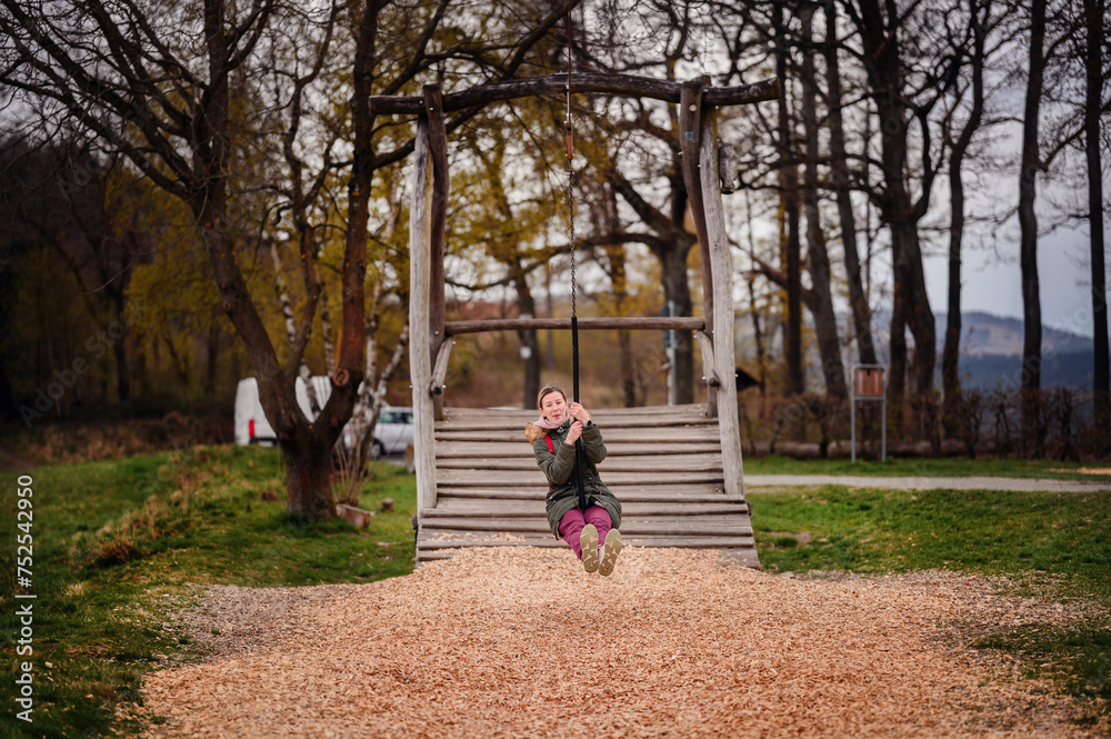 The pure joy of a carefree swing ride is captured as a young woman kicks her feet up, immersed in the simple pleasure of a childhood favorite activity The pure joy of a carefree swing ride is captured as a young woman kicks her feet up, immersed in the simple pleasure of a childhood favorite activity