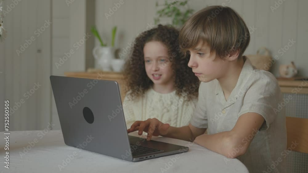 Happy joyful teenagers siblings playing games on laptop, brother and sister having fun together, mum coming and finishing interrupting, putting books and notes on the table. Time to study for children Happy joyful teenagers siblings playing games on laptop, brother and sister having fun together, mum coming and finishing interrupting, putting books and notes on the table. Time to study for children