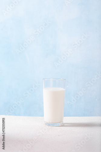Glass jug with milk and a glass of milk on a light blue background