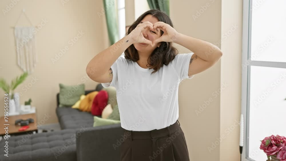 Beautiful young hispanic woman happily gesturing heart symbol indoors, smiling and standing in love - a romantic at-home concept Beautiful young hispanic woman happily gesturing heart symbol indoors, smiling and standing in love - a romantic at-home concept