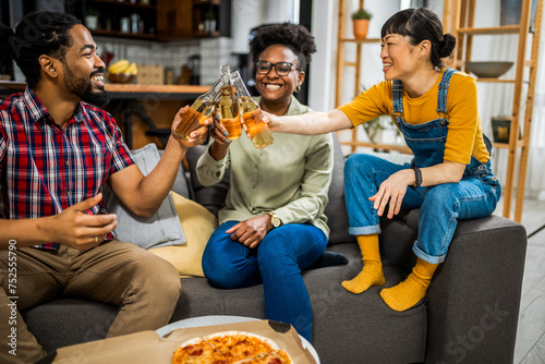 Multiethnic group of friends toasting with beer at pizza party.