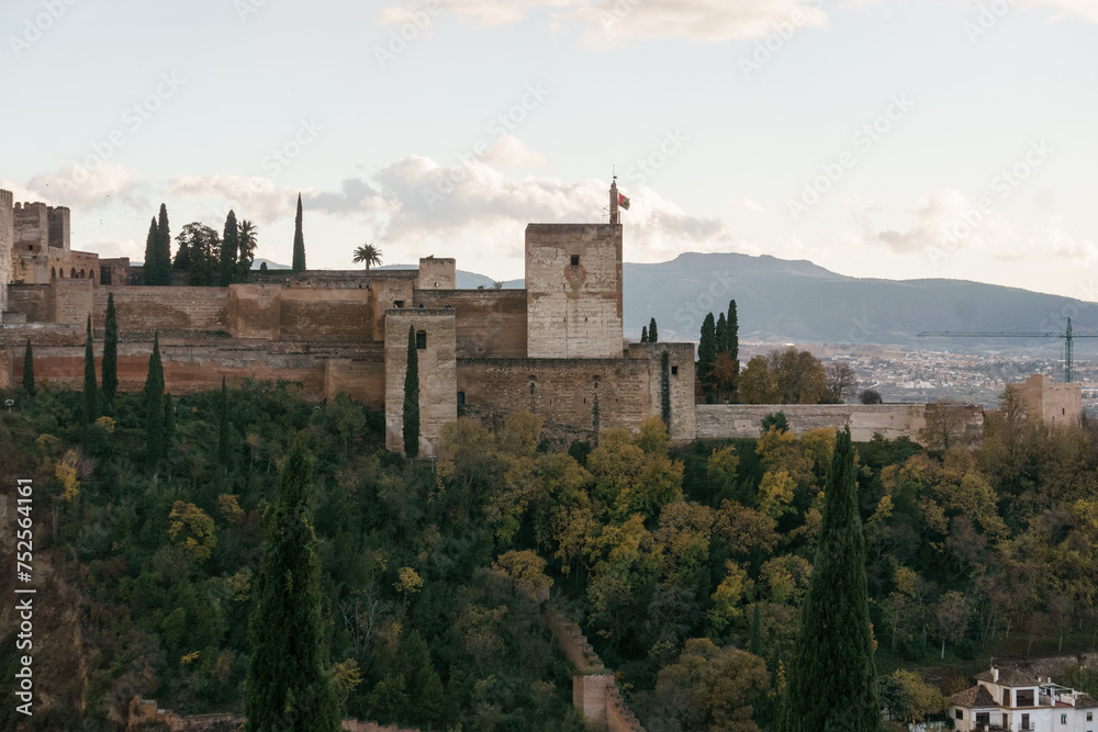 The fortress of Alhambra on a hill top seen from the quarter Albaicin with mountains of Sierra Nevada in background, Granada, Andalusia, Spain