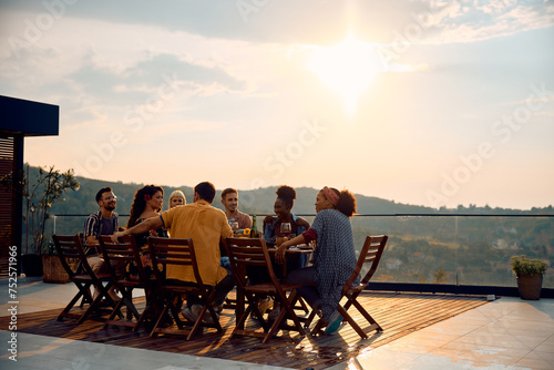 Multiracial group of friends having lunch at dining table on patio. © Drazen
