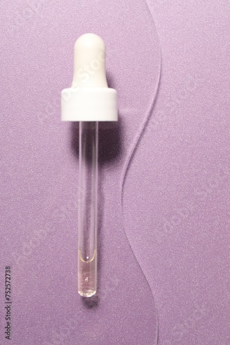 Pipette with moisturizing serum on violet background, top view