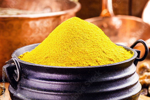 Turmeric powder in molten metal bowls on wooden table, spices, turmeric, turmeric root photo