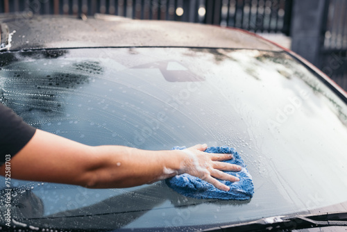 Hand washing a car windshield with soap and water photo
