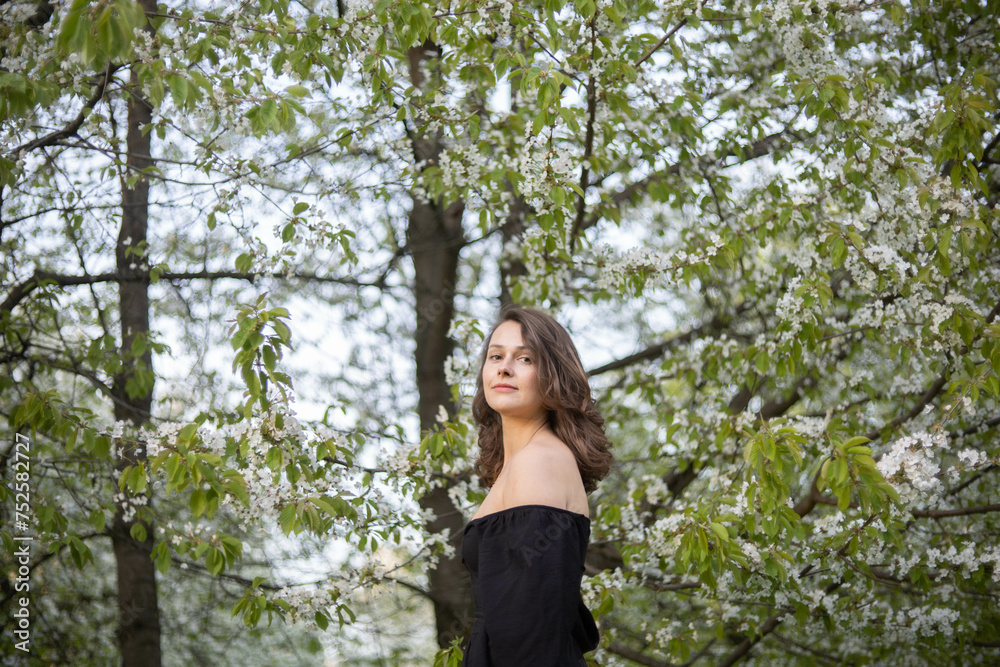 young beautiful woman in a blooming park in white blossoms in spring. young beautiful woman in a blooming park in white blossoms in spring.