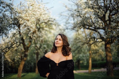 young beautiful woman in a blooming park in white blossoms in spring.