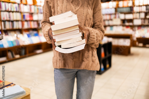 Person holding a stack of books in a library photo