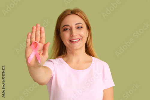 Mature woman with pink ribbon on green background. Breast cancer awareness concept