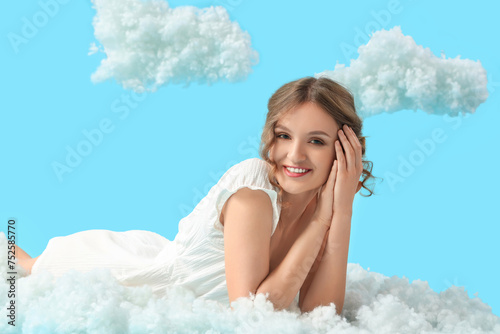 Young woman with white clouds lying on blue background