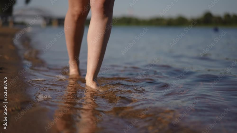 Close-up of women's feet walking barefoot in the water along the sandy bank of the river. Slow motion Close-up of women's feet walking barefoot in the water along the sandy bank of the river. Slow motion