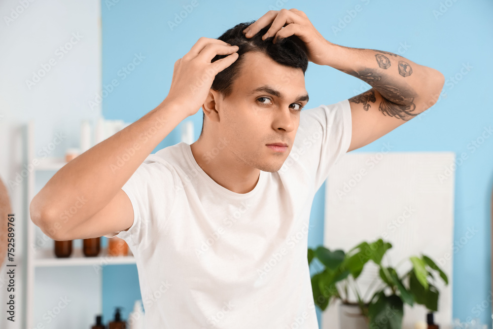 Young man with hair loss problem in bathroom, closeup