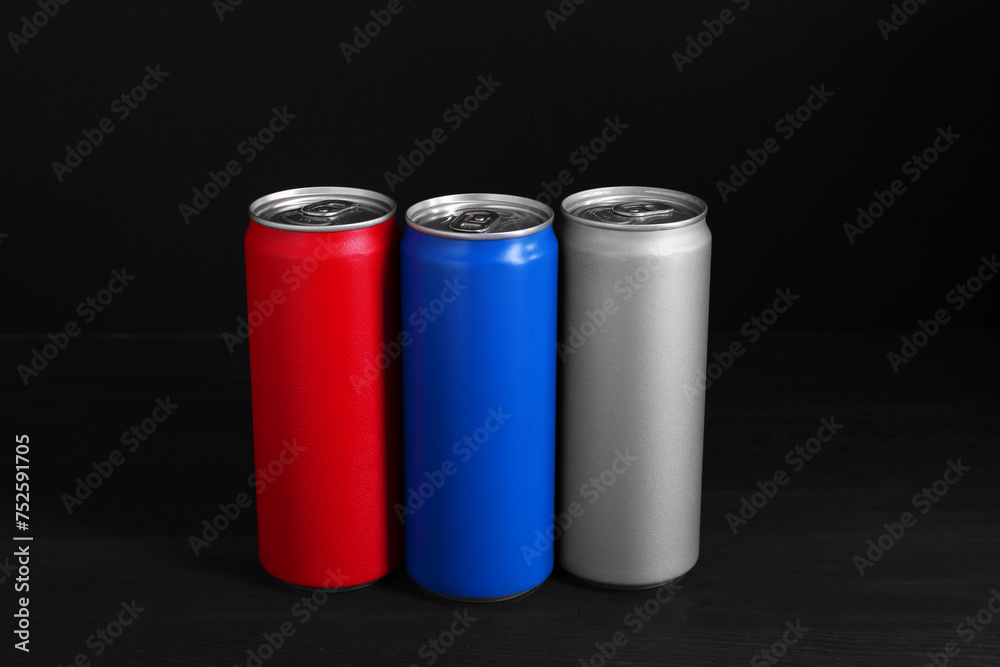 Energy drinks in colorful cans on black wooden table Energy drinks in colorful cans on black wooden table