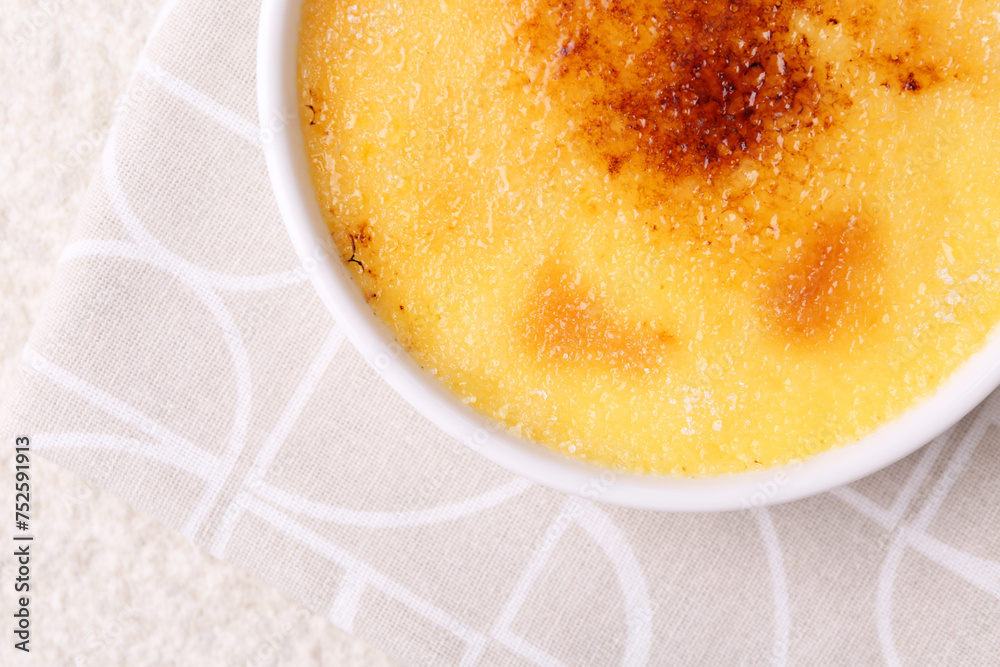 Delicious creme brulee in bowl on light textured table, top view. Space for text Delicious creme brulee in bowl on light textured table, top view. Space for text