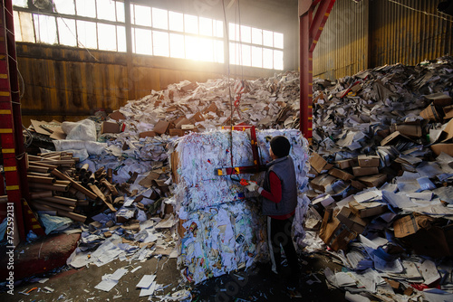 Worker packing paper at wastepaper recycling factory photo