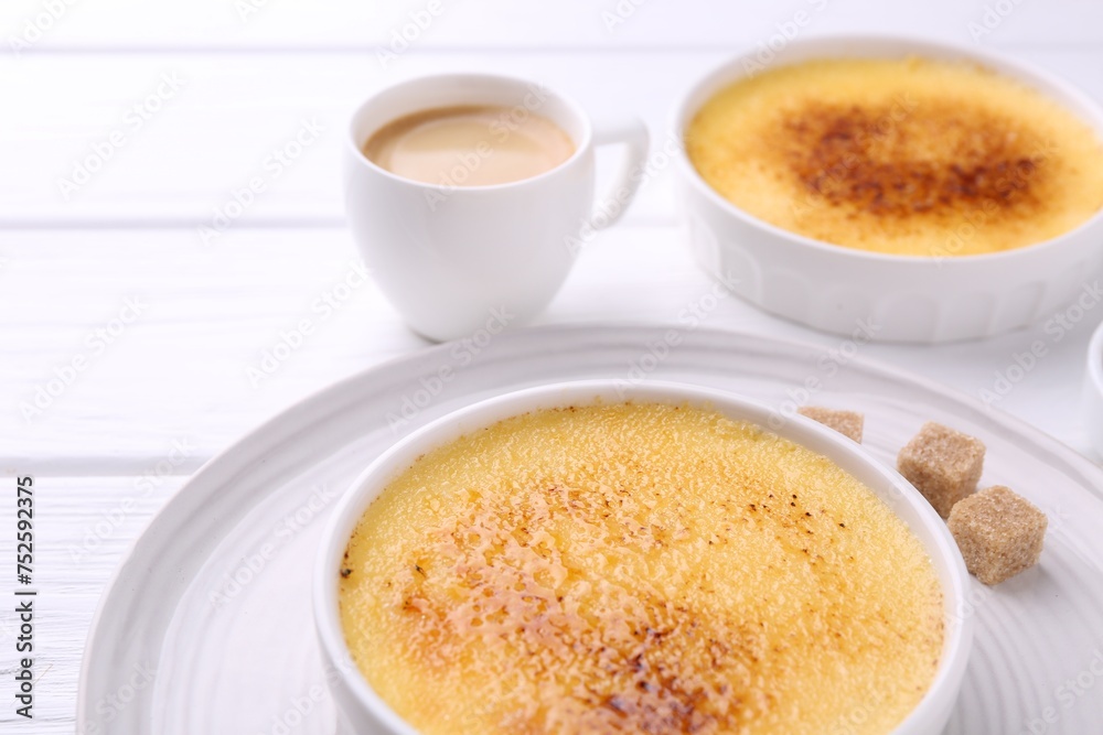 Delicious creme brulee in bowls, sugar cubes and coffee on white wooden table, closeup Delicious creme brulee in bowls, sugar cubes and coffee on white wooden table, closeup