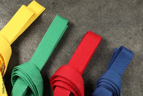 Colorful karate belts on gray background, flat lay photo